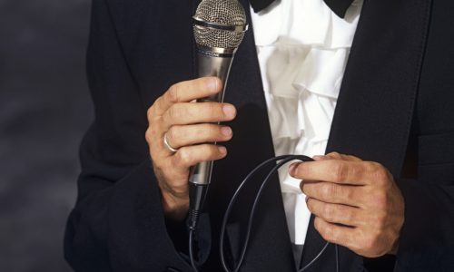 Conferencier in elegant suit holding the microphone